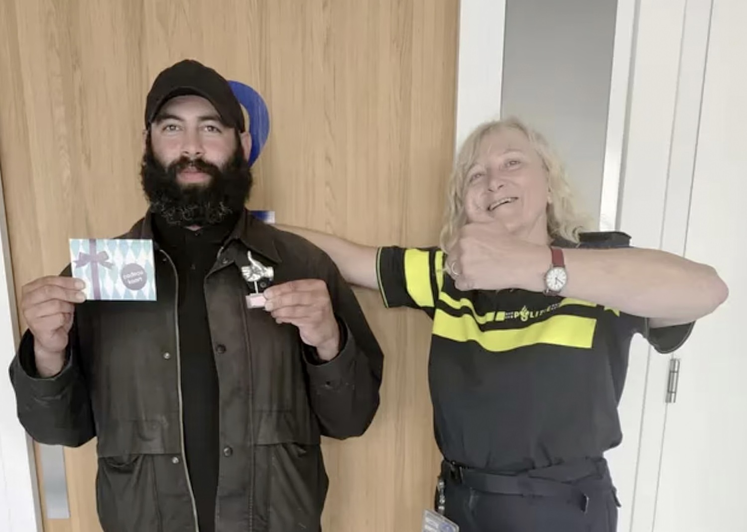 Hadjer Al-Ali (trái) nhận biểu tượng Ngón tay bạc và phiếu quà tặng sau khi tới đồn cảnh sát Amsterdam trả lại chiếc ví chứa 2.100 USD. Ảnh: Dutch News