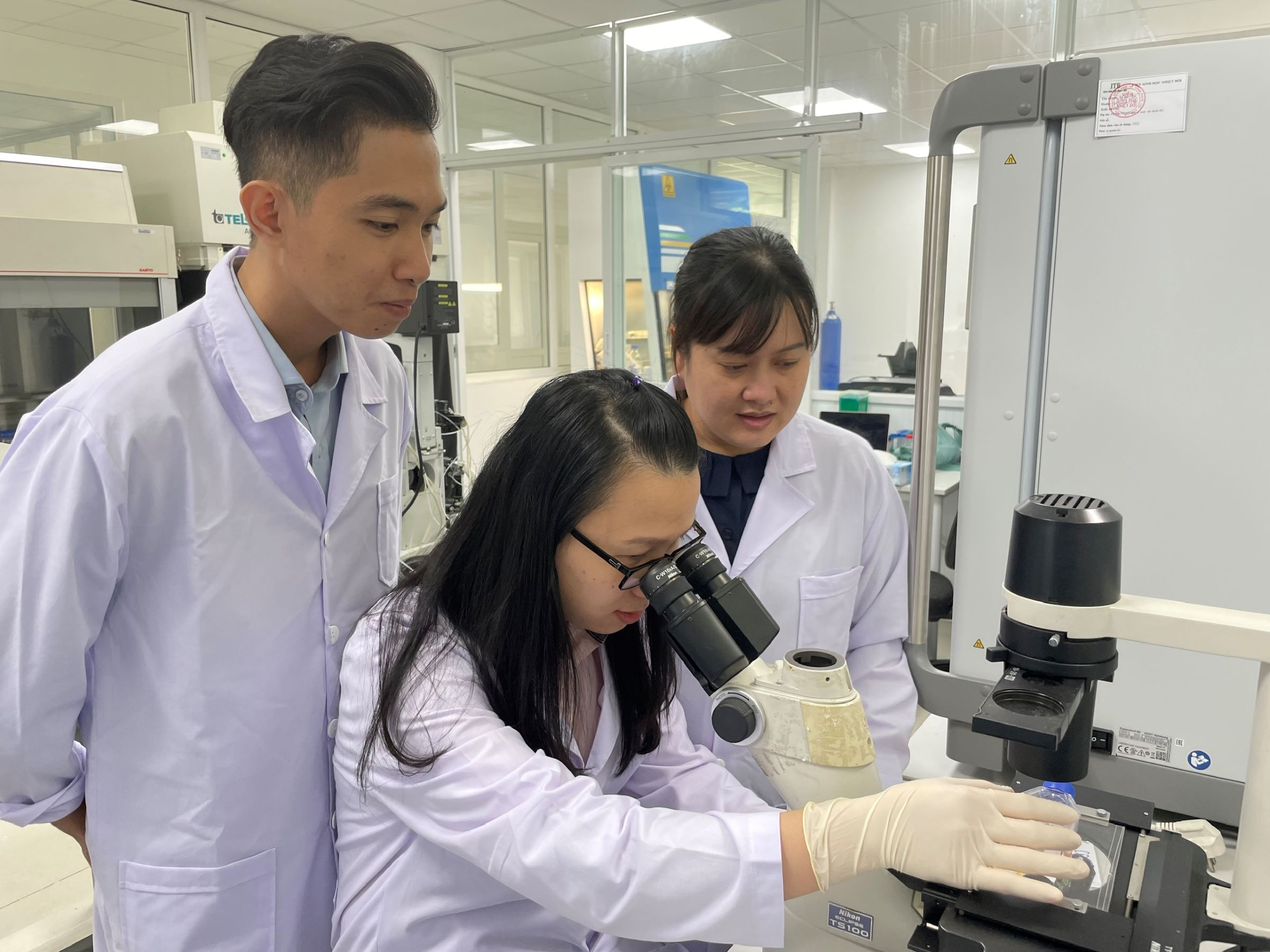 TS Đặng Thị Tùng Loan (phải) cùng các thành viên nhóm nghiên cứu quan sát sự phát triển tế bào gốc nang tóc trên kính hiển vi. Ảnh: Hà An