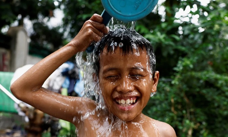 Một bé trai đổ nước lên đầu để giải nhiệt ở khu vực đông dân ở Jakarta hôm 16/5/2024. Ảnh: Willy Kurniawan/Reuters